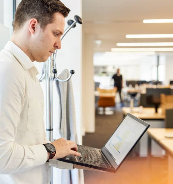 A person standing holding a laptop in an office
